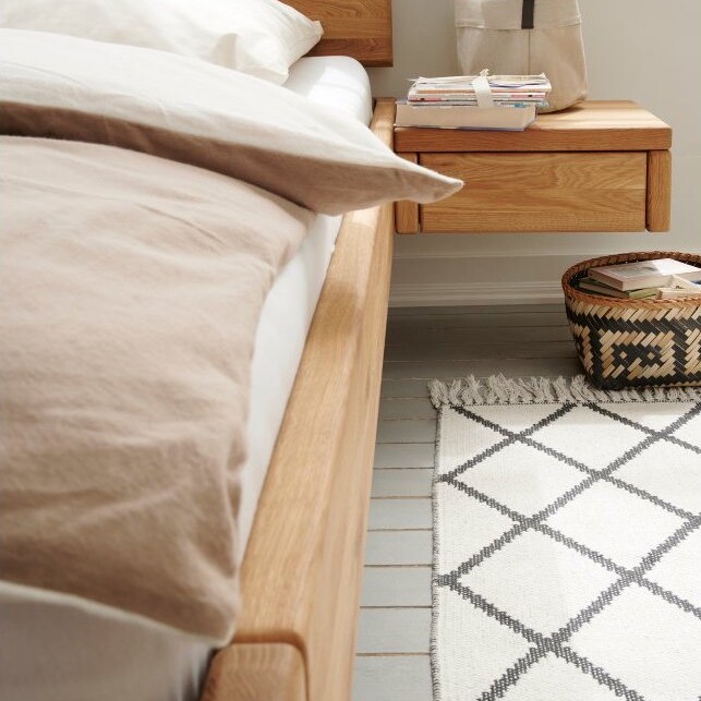 Holzbett mit gepolstertem Kopfteil in einem modern eingerichteten Schlafzimmer