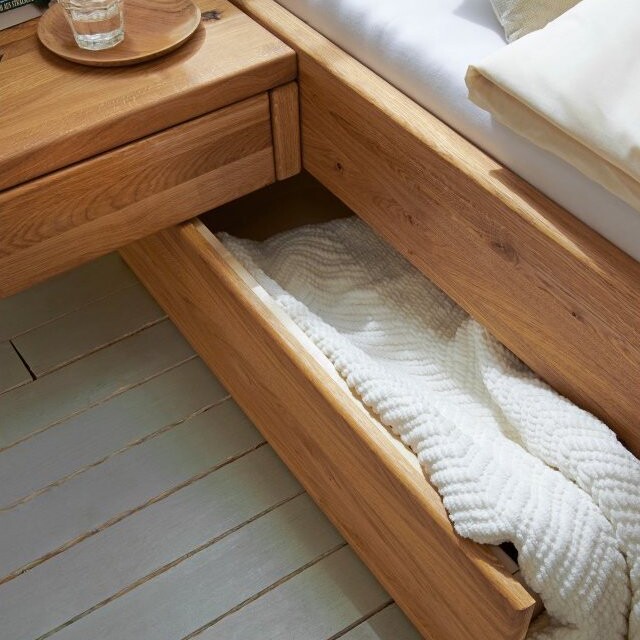 Geöffneter Stauraum unter einem Holzbett mit Schublade