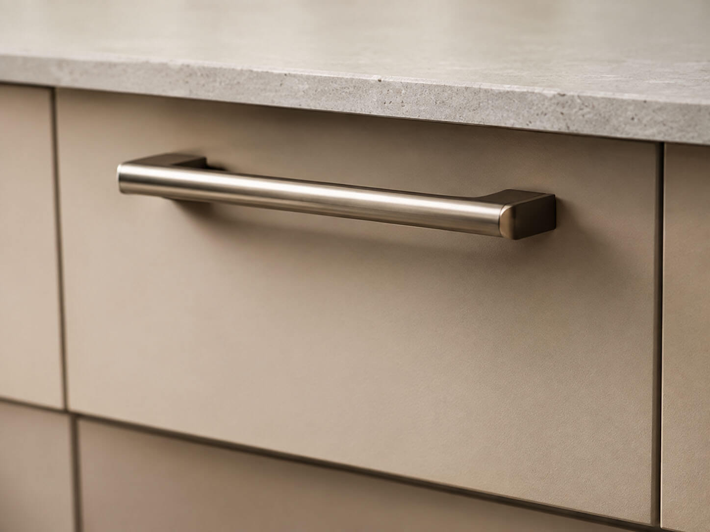 Detailaufnahme eines schlanken Metallgriffs an einer Küchenfront