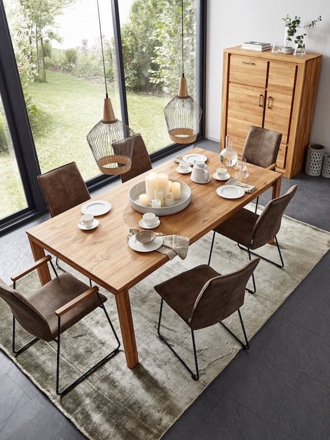 Großer Holzesstisch mit Stühlen und gedecktem Tisch in einem hellen Esszimmer