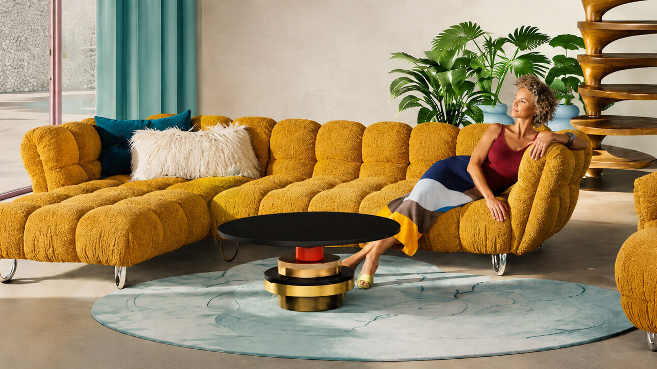 Gelbes Bretz Sofa mit geschwungenen Polstern in einem farbenfrohen Wohnzimmer
