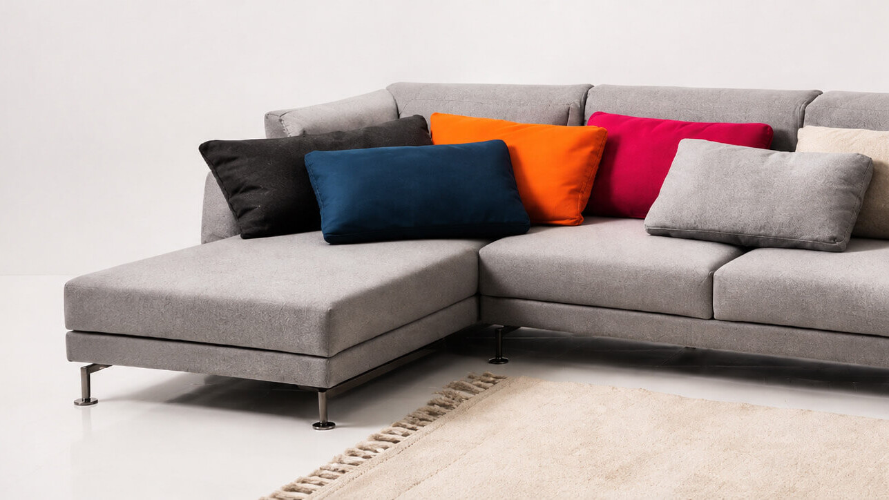 Modernes br&uuml;hl Sofa mit grauem Bezug und farbigen Zierkissen