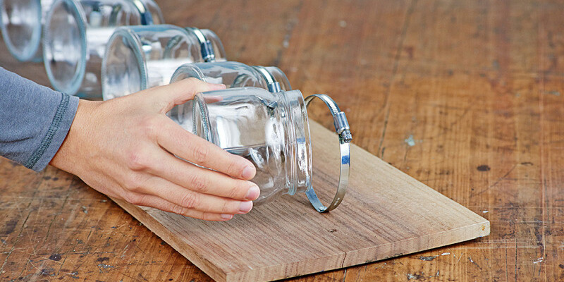 Hand setzt Einmachgläser auf zugeschnittenes Holz für selbstgemachtes Badezimmerregal“