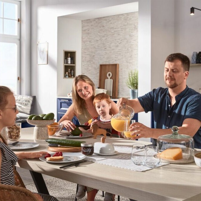 Familie in einer hellen modernen Küche mit Kücheninsel und Essbereich