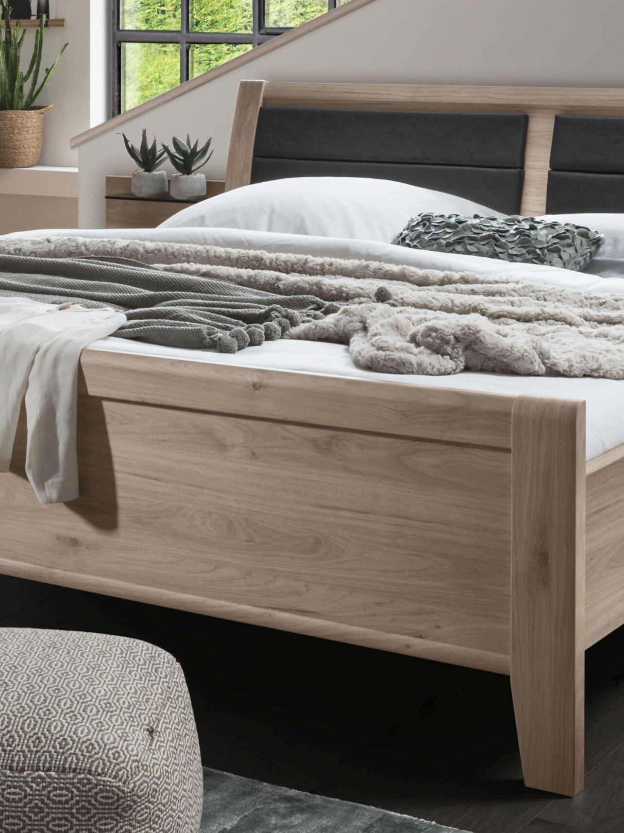 Massivholzbett mit natürlicher Holzmaserung in einem modern eingerichteten Schlafzimmer
