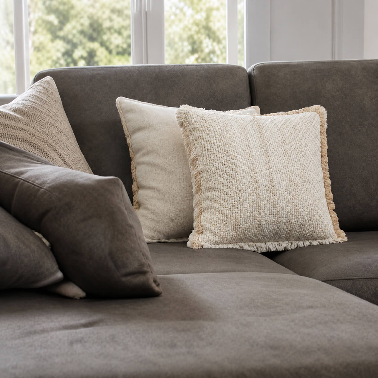 Graues Sofa mit hellen Kissen in einem modern eingerichteten Wohnzimmer